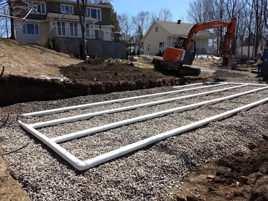 New drain field lines laid in gravel beside a house